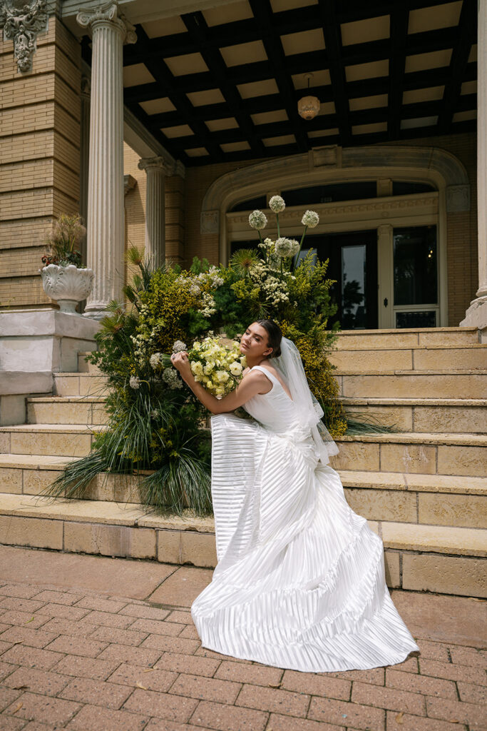bride with luxury floral design on the steps of the Cotton Mansion, minnesota wedding